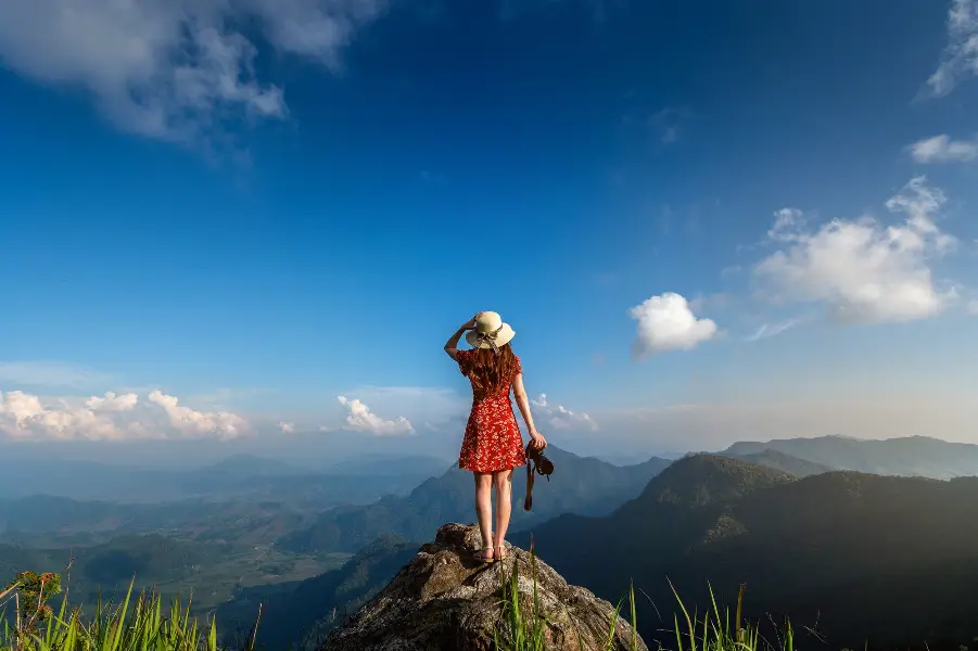 Woman hand holding camera and standing on top of the rock in nature. Travel concept.